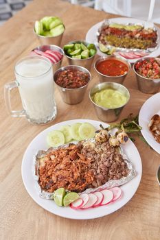 variety of delicious typical mexican food and ingredients such as salsas, red, green, guacamole, lemon, tomato and onion.