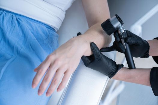 A dermatologist examines a patient's mole through a dermatoscope