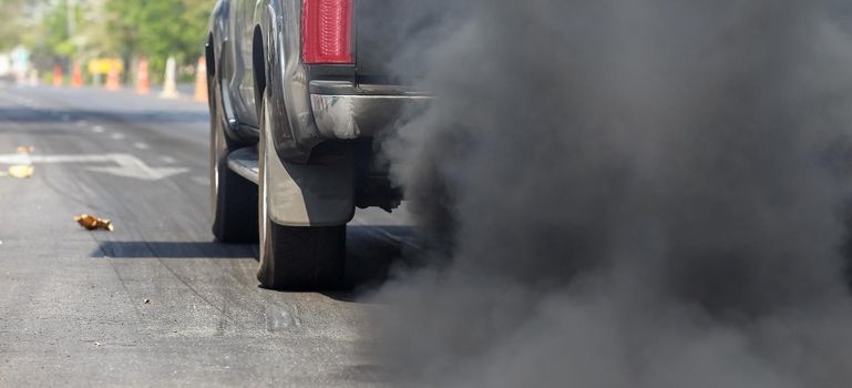 Air pollution from vehicle exhaust pipe on road.