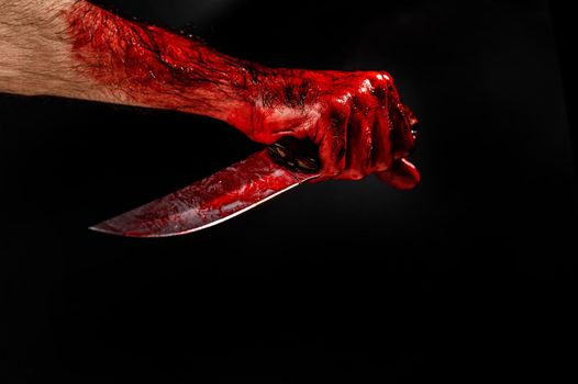 Man holding knife with bloody hand on black background