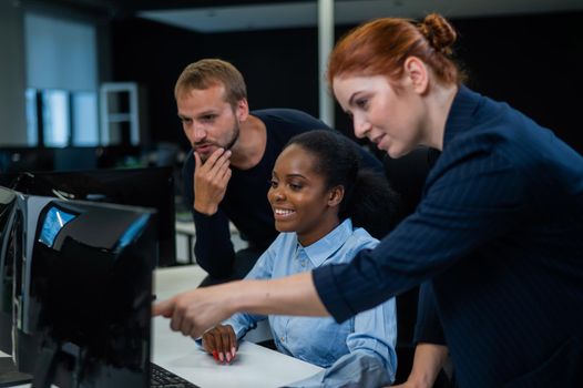 Colleagues discuss work. African young woman, caucasian and red-haired caucasian communicate in the office