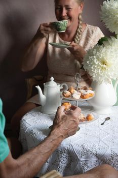 tea break in the English style, still life with flowers and donuts in the morning sun, homemade cakes, married couple drinking tea together at breakfast in english style, beautifully set table