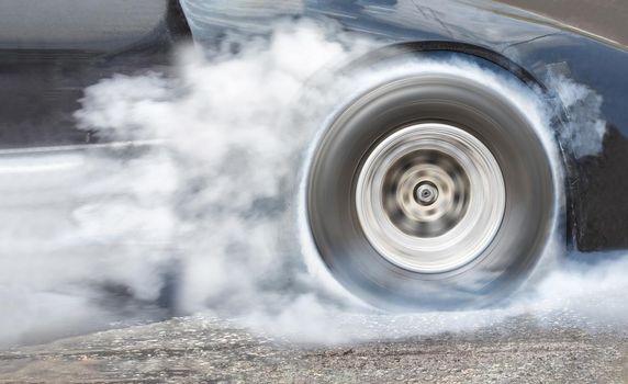 Drag racing car burns rubber off its tires in preparation for the race