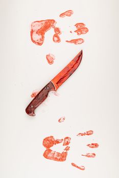 Bloody knife and hand prints in blood on a white table
