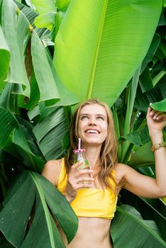 Summer vacation. Beautiful woman in yellow swimsuit with long hair and palm leaves. Beautiful caucasian girl in stylish swimwear in tropical nature