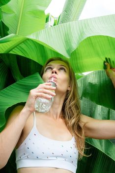 Summer vacation. Beautiful woman in white swimsuit with long hair and palm leaves. Beautiful caucasian girl in stylish swimwear in tropical nature