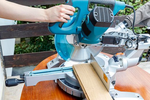 Miter saw in the process of sawing off a wooden part. 