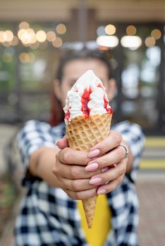 Attractive young woman in summer clothes and sunglasseseating ice cream at street