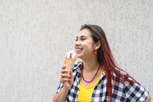 Attractive young woman in summer clothes and sunglasseseating ice cream at street