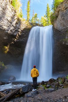 Beautiful waterfall in Canada, couple visit Helmcken Falls, the most famous waterfall in Wells Gray Provincial Park in British Columbia, Canada. young men standing looking at a waterfall