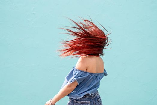 Attractive young woman in summer clothes and sunglasses, dancing on blue wall background at street