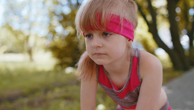 Athletic fitness sport motivated runner child girl training, preparing to run race marathon. Workout cardio in morning park. Toddler kid jogger enjoying healthy lifestyle. Active children motivation
