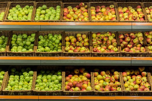 Shelves boxes with fruit colorful apples in the supermarket store on the counter