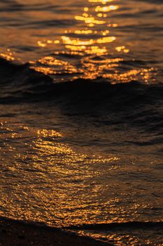 Ripple sea ocean water surface with golden sunset light. Sea waves close up