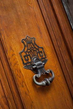 Old wooden door of a French mansion and wrought iron knocker