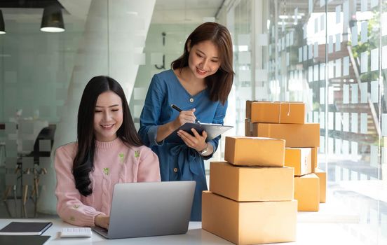 Portrait of Starting small businesses SME owners, two Asian woman check online orders Selling products working with boxs freelance work at home office, sme business online small medium enterprise.