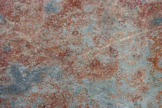 Abstract background of peeling old brown paint with blue spots showing through.