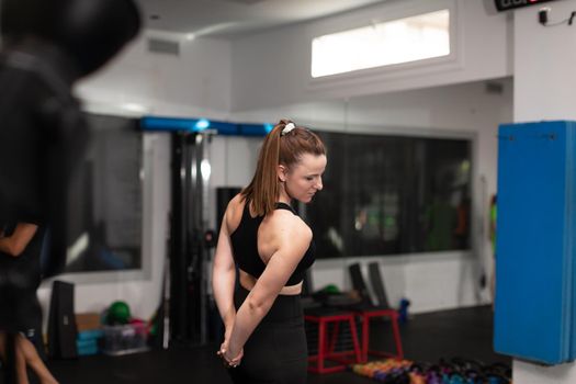 A female trainee warming up and stretching her arms before exercising at the local sport and fitness center