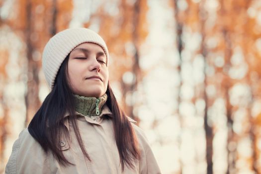 Girl enjoys fresh autumn air while walking in the park.