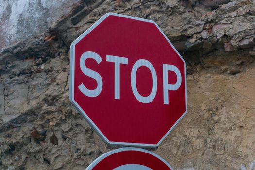 Red stop sign on the background of a destroyed brick wall close up