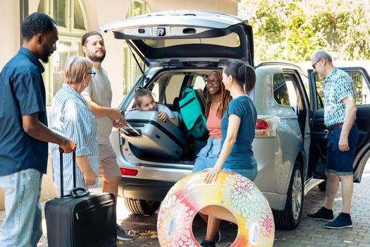 Mixed family and friends going on holiday, preparing vehicle with bags and luggage to go on summer vacation. Multiethnic people travelling on journey adventure with baggage in automobile.