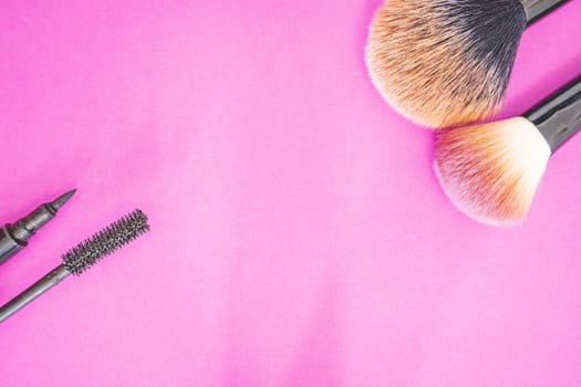 Flatlay of make up and beauty products on a pink background.