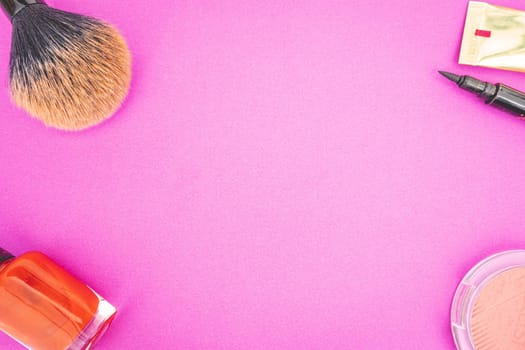 Flatlay of make up and beauty products on a pink background.