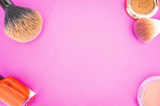 Flatlay of make up and beauty products on a pink background.