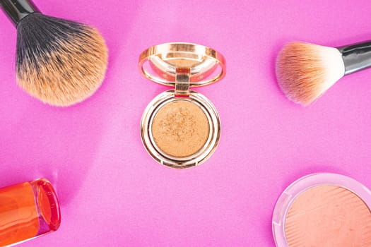 Flatlay of make up and beauty products on a pink background.