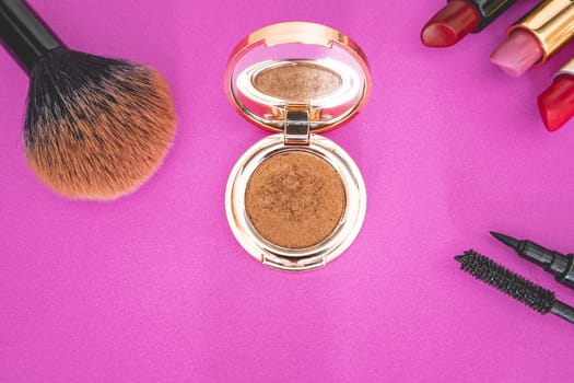 Flatlay of make up and beauty products on a pink background.