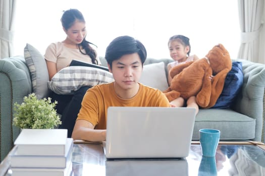 Concept of work from home and home family education. father mother and son are sitting at the desk. Business woman works on the Internet in a laptop.