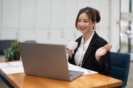 Asian female talking about sale report in video conference using laptop online meeting in video call. Working from home remotely