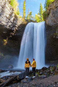 Moul Falls Canada is a Beautiful waterfall in Canada, couple of visits to Moul Falls, the most famous waterfall in Wells Gray Provincial Park. a couple of men and women standing by a waterfall