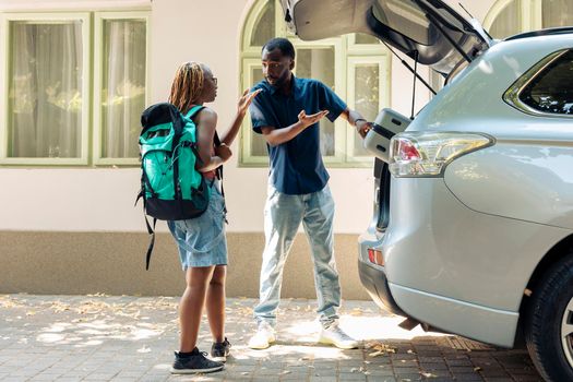 Life partners loading baggage in car trunk, travelling on summer vacation with trolley and bags. Couple leaving on holiday adventure with vehicle, feeling excited about destination.