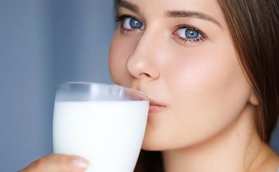 Happy young woman drinking milk or protein milk shake cocktail, healthy drink for diet and wellness concept