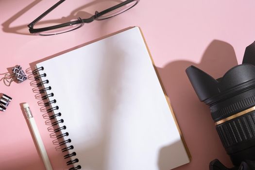 Blank notebook, glasses and camera on desktop top view. Learning photography concept.