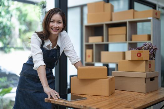 Portrait business Asian woman with parcel shipping box before send to customer. Entrepreneur small business working at home