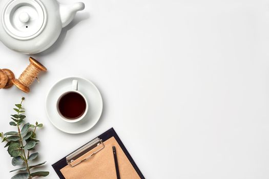 Still life with tea cup and the contents of a workspace composed. Different objects on white table. Flat lay. Top view. Copy space