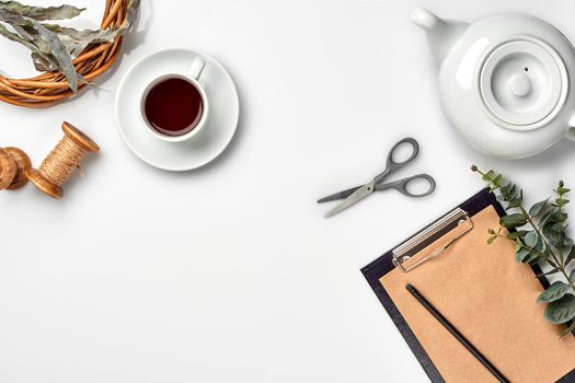 Still life with tea cup and the contents of a workspace composed. Different objects on white table. Flat lay. Top view. Copy space