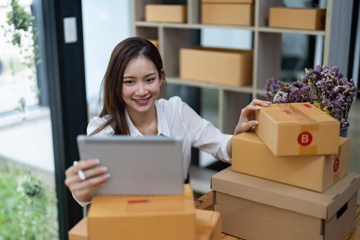 Portrait business Asian woman with parcel shipping box before send to customer. Entrepreneur small business working at home