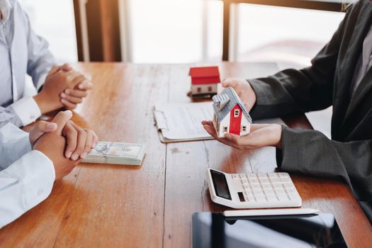 The real estate agent is showing the house model to the customer.