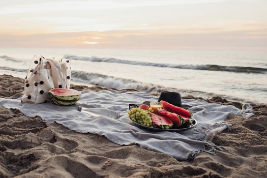 Picnic Set with Fruits by the Sea at Early Morning, Preparing to Sunrise on the Sandy Beach