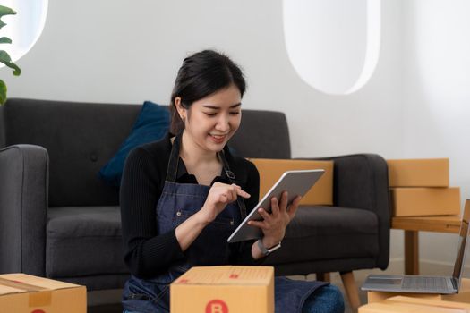 Freelance woman seller check product order, packing goods for delivery to customer. Online selling, e-commerce, shipping concept.