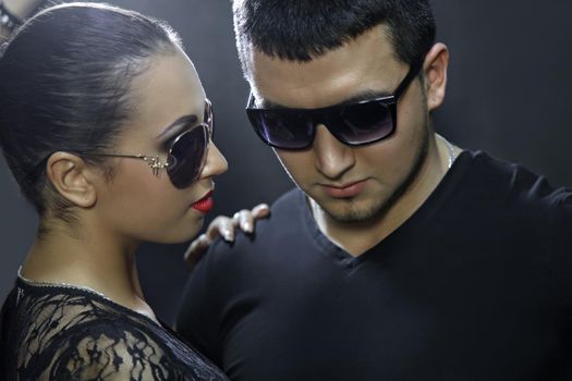 Attractive young couple wearing sunglasses. Girl looks at man