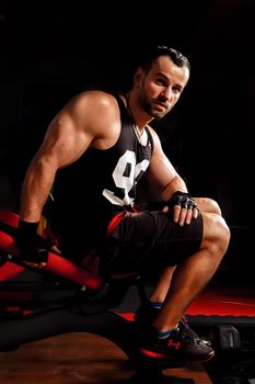 Close up portrait of a fit young man working out in sports simulators and looking at the camera on dark background