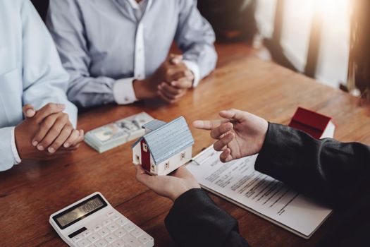 The real estate agent is showing the house model to the customer.