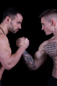 Arm wrestling. Two bodybuilders shake hands and look into each other's eyes