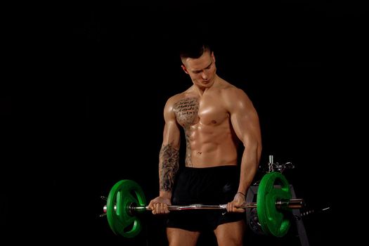 Close up of young muscular man lifting the barbell over dark background