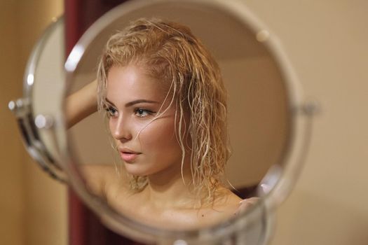 Portrait of a beautiful attractive sexy and sensuality young adult pretty blonde woman after bath relaxing and loks in the mirror