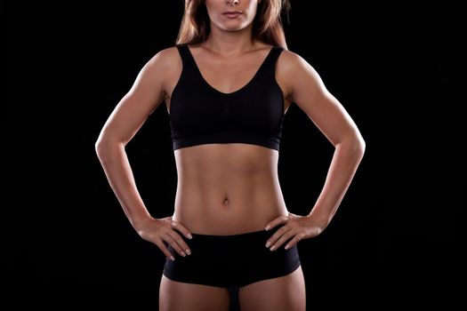 Girl athlete in great shape posing on a dark background